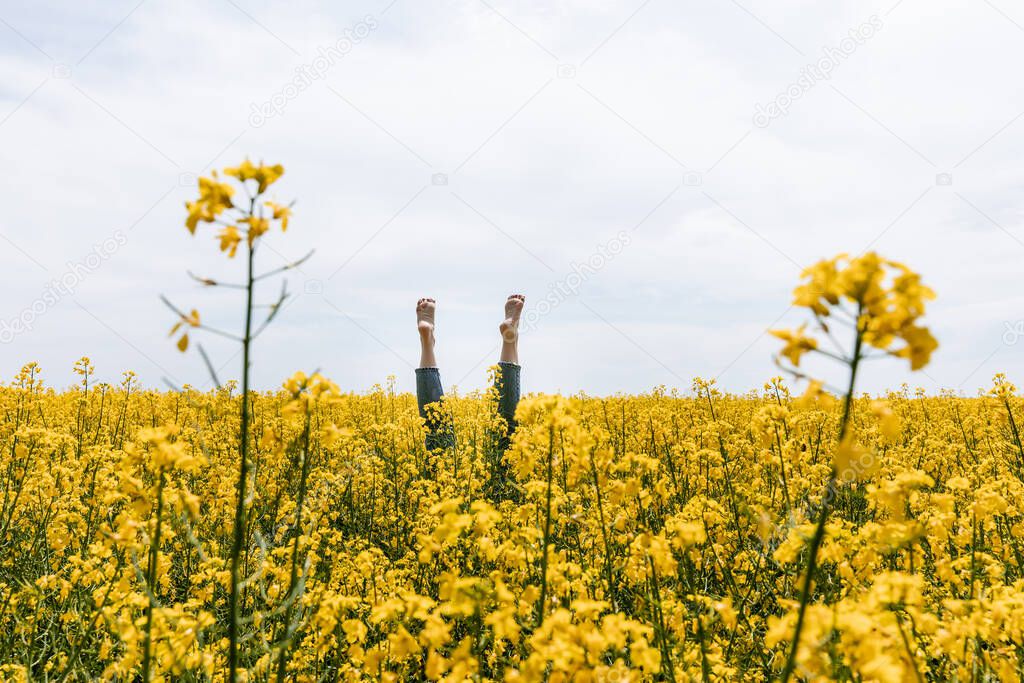 selective focus of woman with bare feet near yellow flowers in field 