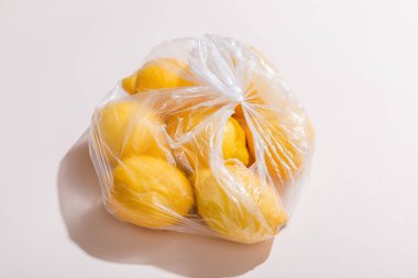 Gri masadaki plastik torbada taze sarı limonlar  