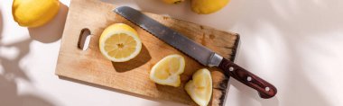 top view of cutted lemons on wooden board with knife on grey table, panoramic concept clipart