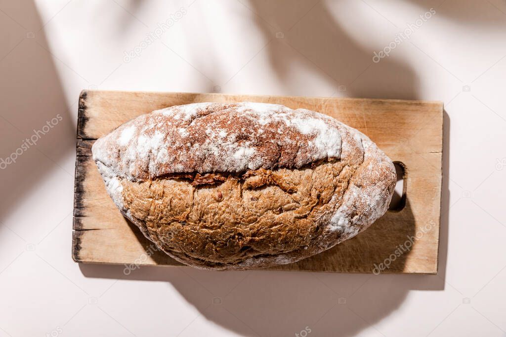 top view of bread on cutting board on grey table with shadows 