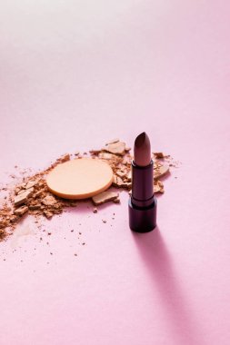 Makyaj süngerinin yanında çatlak yüz pudrası ve pembe ruj. 