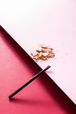 Kırık yüz pudrası ve kırmızı ve pembe kozmetik fırçası 