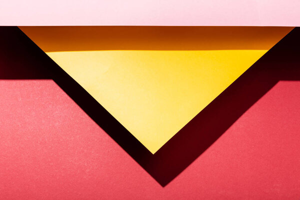 top view of empty yellow and pink paper sheets on crimson 