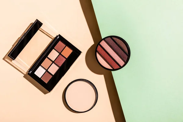 Top view of face powder near eye shadow palettes on pink and blue — Stock Image Top View Face Powder Eye Shadow Palettes Pink Blue Stock Image