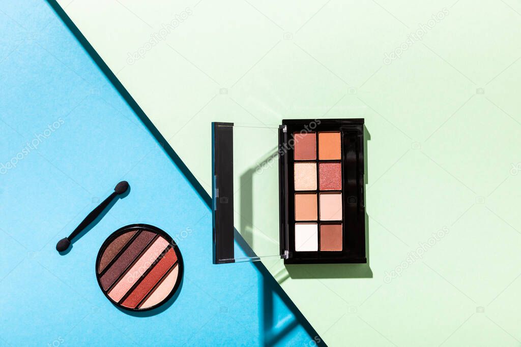 top view of eye shadow palettes and double-sided eyeshadow applicator on blue and green 