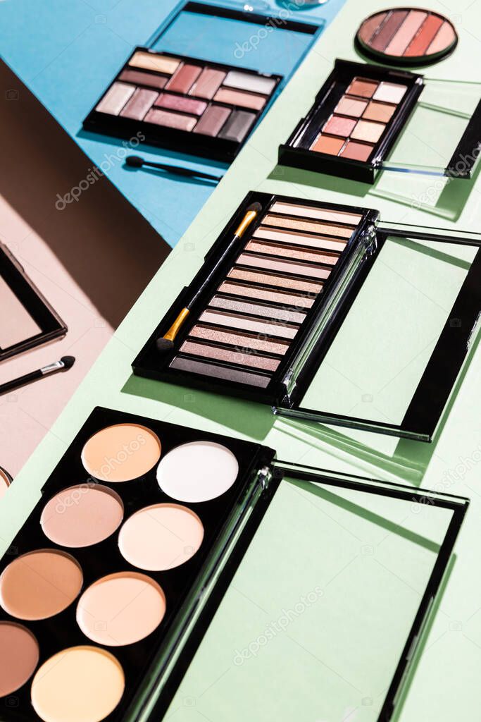 selective focus of eye shadow and blush palettes on green, blue and pink 