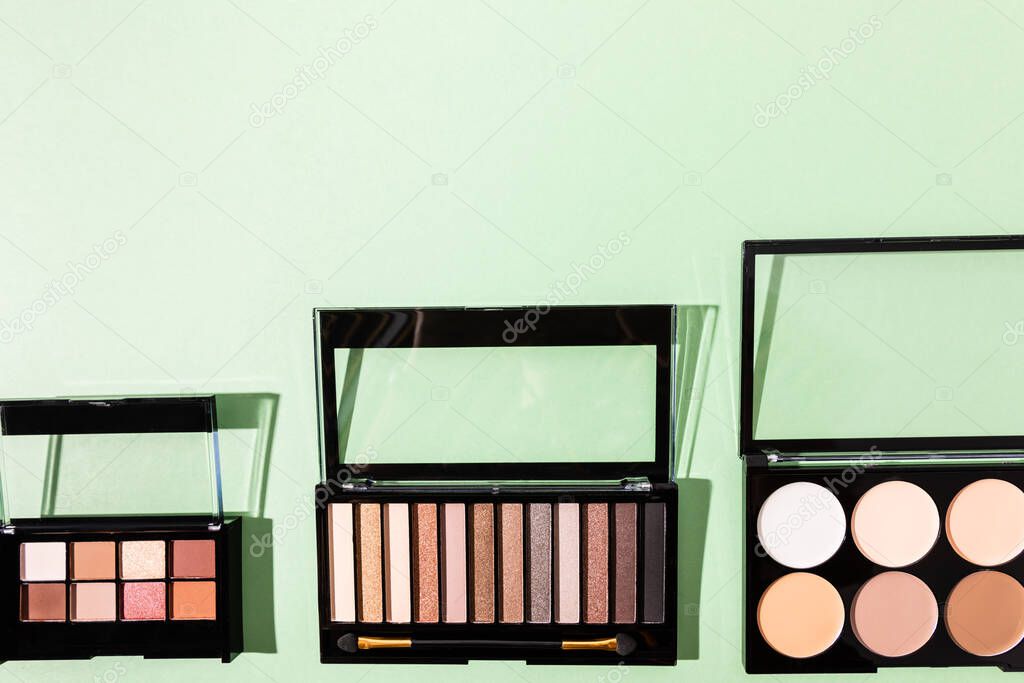 top view of eye shadow and blush palettes on green