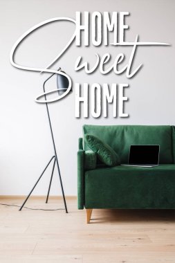 Yeşil kanepe üzerinde boş ekranlı dizüstü bilgisayar, yer lambası ve güzel ev harfleri.