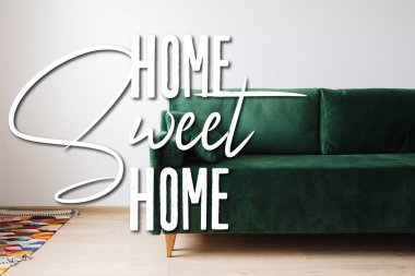Yastıklı yeşil kanepe renkli halıların yanında ve ev yapımı harfler. 