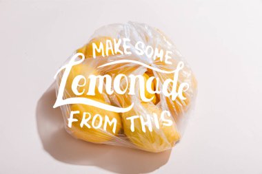 Gri masadaki plastik torbada taze sarı limonlar. Bu harflerden biraz limonata yap.