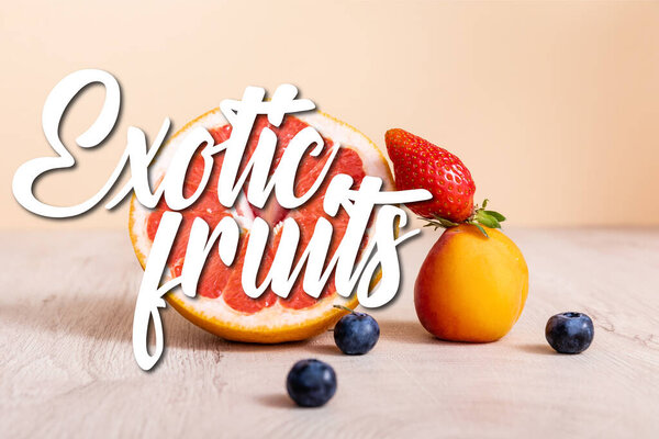 fruit composition with berries, grapefruit and apricot near exotic fruits lettering on beige