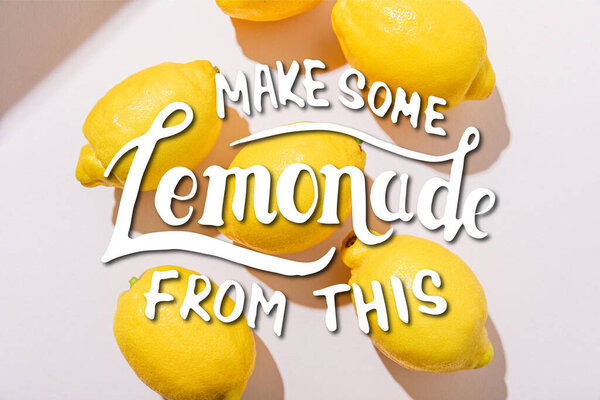 top view of whole fresh lemons on grey table with make some lemonade from this lettering