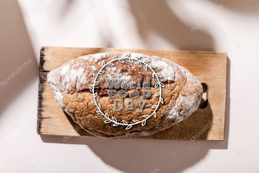 top view of bread on cutting board on grey table with world food day lettering 