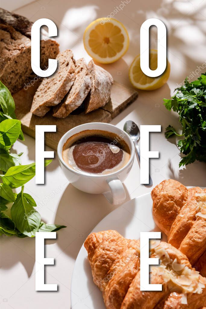 fresh croissants, bread, greenery and cup for breakfast on grey table with coffee lettering