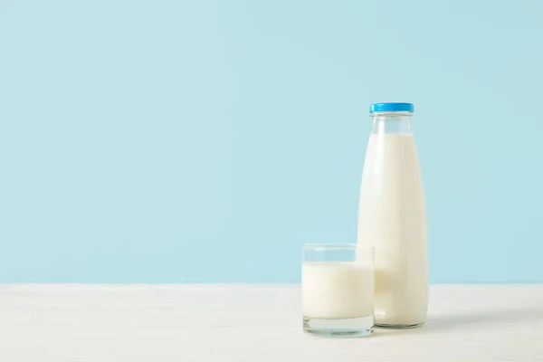 Imagen de primer plano de botella de leche y vaso de leche sobre fondo azul - foto de stock