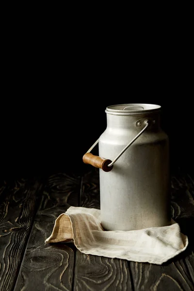 Closeup view of milk in aluminium can on sackcloth on black background — Stock Photo