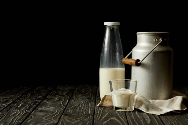 Milch in Flasche, Glas und Aluminiumdose auf Sacktuch auf schwarzem Hintergrund — Stockfoto