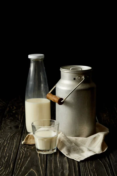 Leche en botella, vidrio y lata de aluminio sobre tela de saco sobre fondo negro - foto de stock