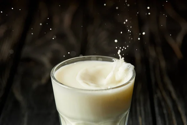 Closeup view of splashing drops of milk from glass — Stock Photo