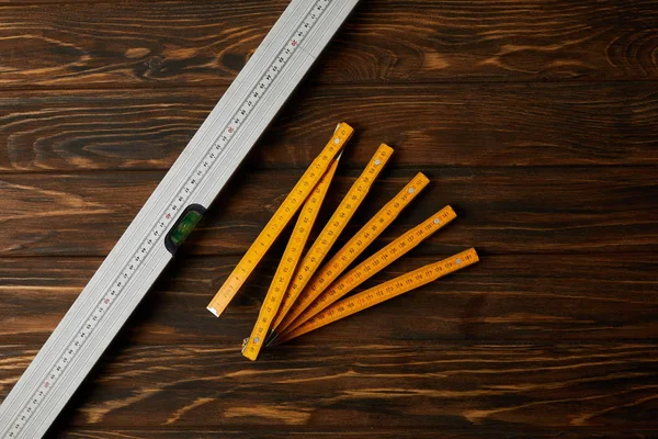 Top view of collapsible meter and spirit level on wooden table — Stock Photo