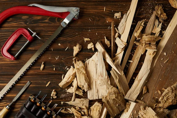 Vue de dessus des ciseaux et de la scie à coping avec des pièces en bois sur la table — Photo de stock