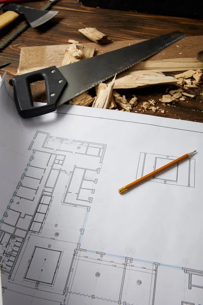 Closeup view of architectural blueprint, pencil, handsaw, axe and coping saw on wooden table — Stock Photo