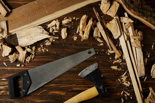 Vista sopraelevata di ascia, sega a mano e pezzi di legno su tavolo marrone — Foto stock