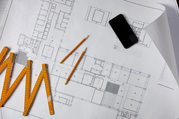 Elevated view of collapsible meter, pencils and smartphone with blank screen on blueprint — Stock Photo