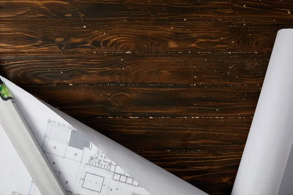 Top view of spirit level and blueprint on wooden brown table — Stock Photo