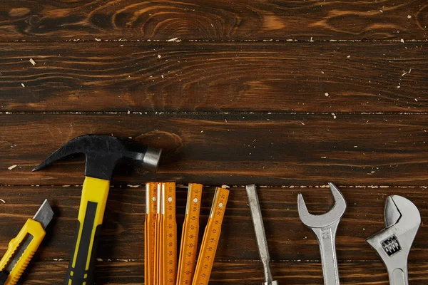 Erhöhte Ansicht von Schreibwarenmesser, Hammer, Meißel, Einstellschlüssel, Schraubenschlüssel und faltbarem Meter auf Holzoberfläche — Stockfoto