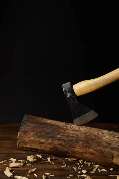 Close up view of sticking axe in log and wooden chips on black background — Stock Photo