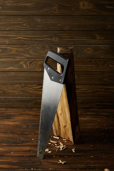 Closeup view of handsaw and log on wooden brown table — Stock Photo