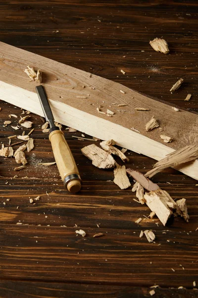 Image rapprochée du ciseau et des morceaux de bois sur la table brune — Photo de stock