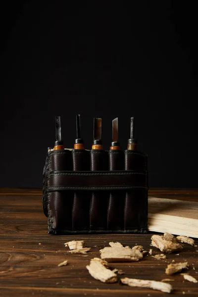 Gros plan de ciseaux dans un étui en cuir et des morceaux de bois sur la table — Photo de stock