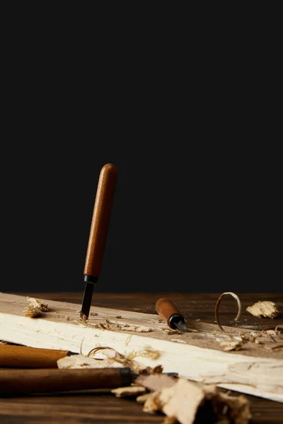 Stemmeisen aus Holz am Tisch auf schwarzem Hintergrund — Stockfoto