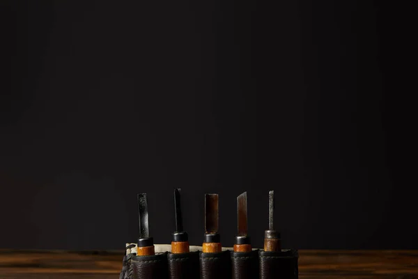 Chisels in leather case at table on black background — Stock Photo