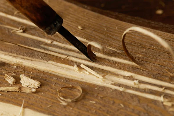 Partial view of chisel sticking in wooden plank with scobs — Stock Photo