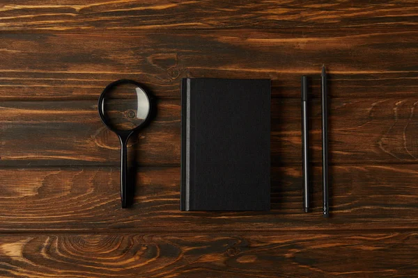 Vista superior de lupa, notebook e material de escritório em mesa de madeira — Fotografia de Stock