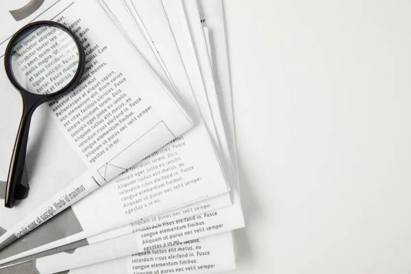 Вид зверху на збільшувальне скло і газети на сірому, інформаційна концепція — стокове фото