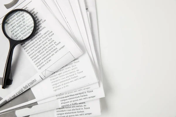 Top view of magnifying glass and newspapers on grey, information concept — Stock Photo