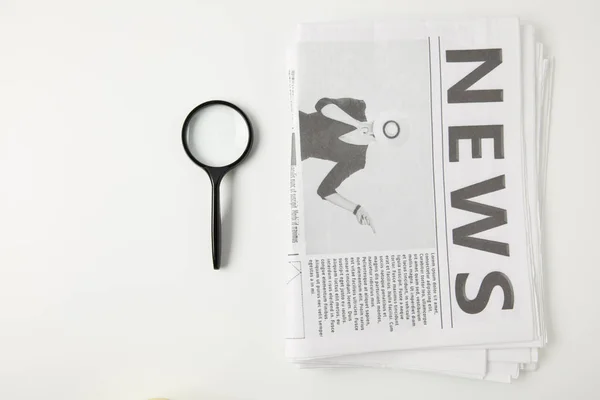 Top view of magnifying glass and newspapers isolated on grey — Stock Photo