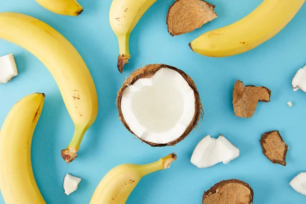 Top view of arranged coconut pieces and bananas isolated on blue — Stock Photo