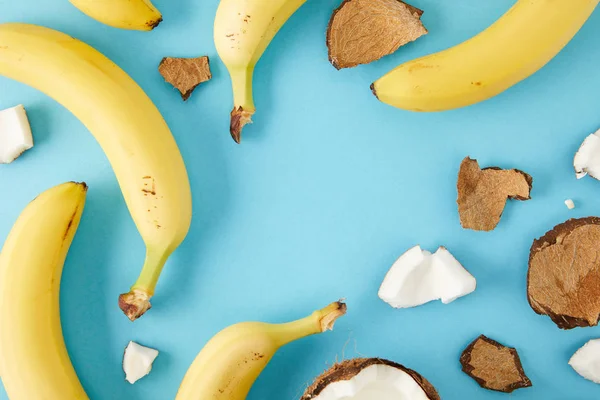 Вид зверху розташовані кокосові шматочки та банани ізольовані на синьому — стокове фото