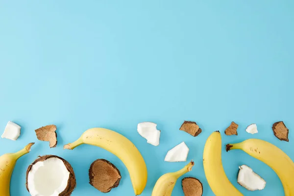 Top view of arranged coconut pieces and bananas isolated on blue — Stock Photo