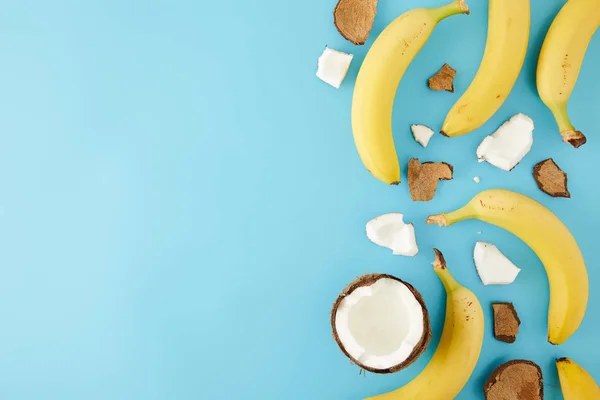 Vista superior de pedaços de coco dispostos e bananas isoladas em azul — Fotografia de Stock
