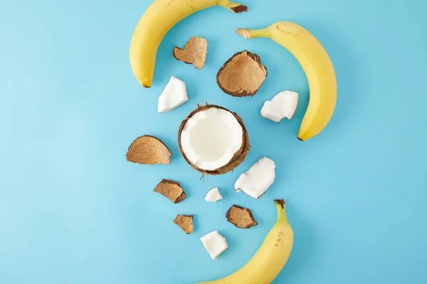 Vista superior de pedaços de coco dispostos e bananas isoladas em azul — Fotografia de Stock