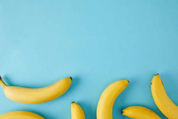 Vista superior de bananas frescas dispostas isoladas em azul — Fotografia de Stock