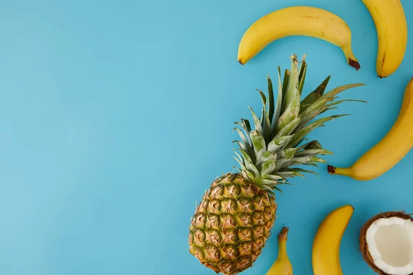 Top view of fresh coconut, bananas and pineapple isolated on blue — Stock Photo