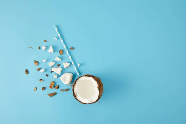 Top view of arranged coconut pieces and straw isolated on blue — Stock Photo