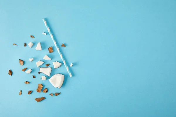 Top view of arranged coconut pieces and straw isolated on blue — Stock Photo